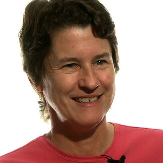 Headshot of person with short hair and brightly colored top.