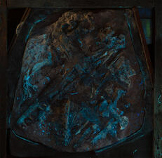 Partial fossil skeleton in a wooden crate, with the fossil contained in limestone/carbonate, shown in UV illumination glowing in the dark.