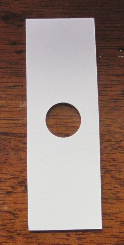 A barrier face for specimen slides, rectangular shaped with a circular hole cut in the center.