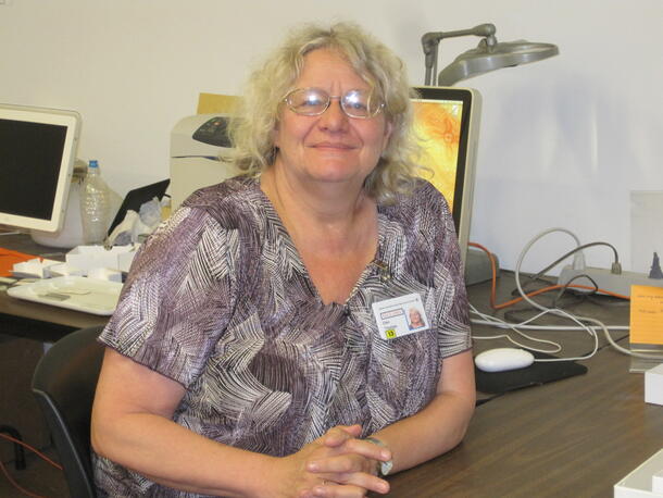 Woman at desk smiling at camera. Dr. Ellen Thomas, Yale University, supervised the Museum’s microfossil collection conservation and digitization in 2013.