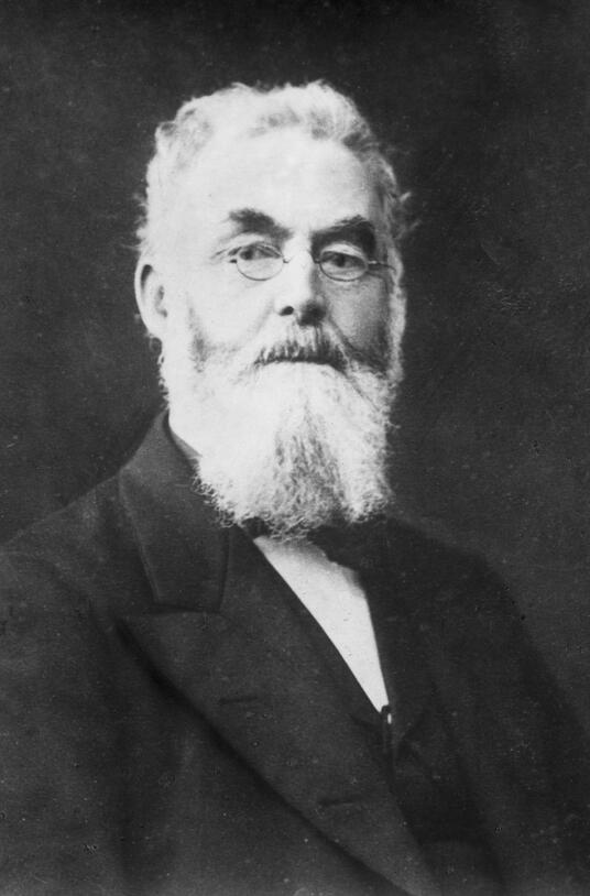 Black-and-white photo of a bearded man in spectacles.