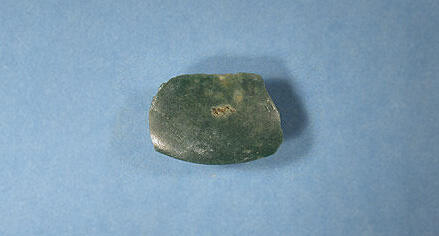 A piece of jadeite jade, dark green with lighter green spots, smoothed at the edges and likely used as an ax head between 250-500 AD, in Antigua.