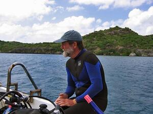 A man in a wetsuit sitting on the edge of a motorboat.