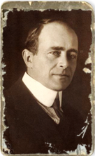 A period bust shot of a man, Robert Falcon Scott, posing for the camera in a starched collared shirt, a necktie, and jacket.