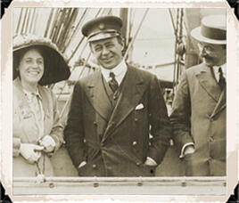 Captain Robert Falcon Scott (center) standing on deck of ship with wife Kathleen Scott (left), and another man (right).