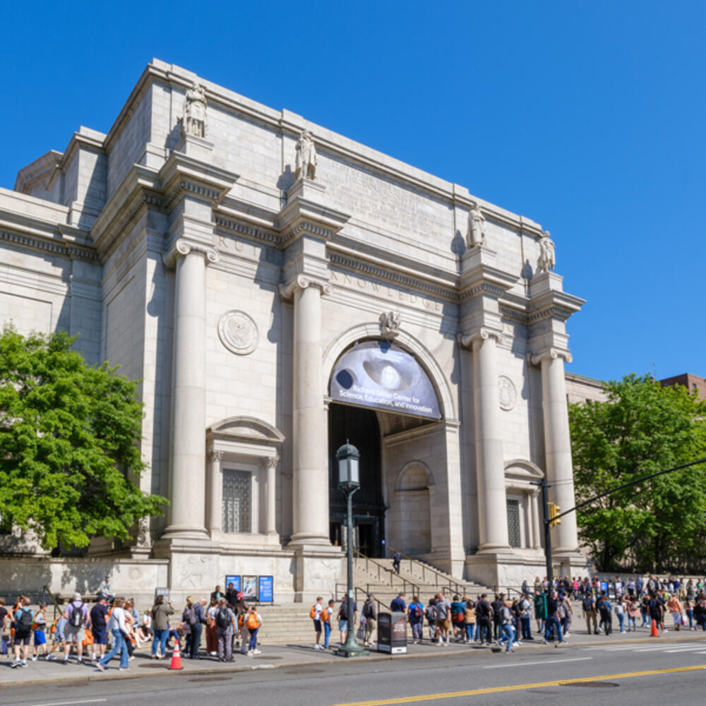 Central Park West Museum facade in the spring with a crowd of people lined up along the sidewalk.