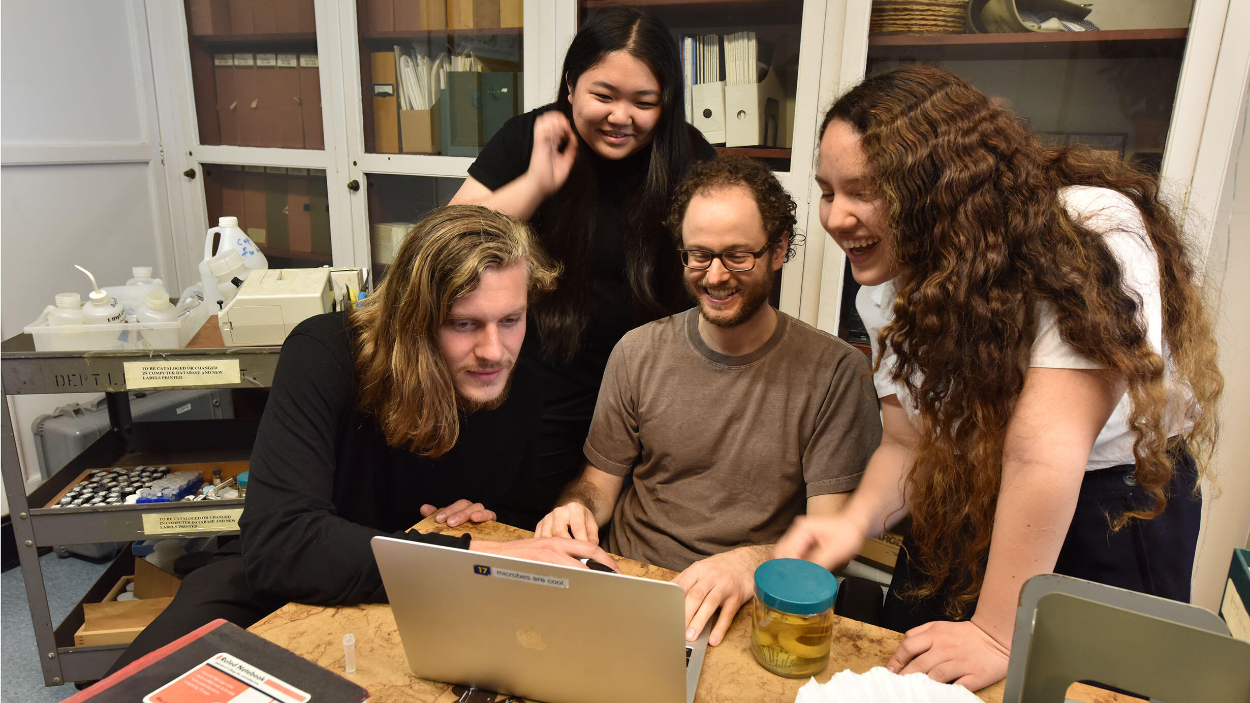 A SRMP instructor shows three students something on their laptop.