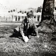 Archie Roosevelt in the White House Garden seated beside a tree, petting a rabbit.