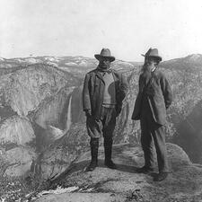 Theodore Roosevelt (left) and John Muir (right) stand on a cliff in Yosemite.