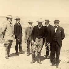 Theodore Roosevelt with five other people, all wearing suits and hats, at the Grand Canyon. 