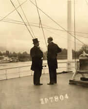 Theodore Roosevelt and Gifford Pinchot stand next to one another on the deck of a boat.