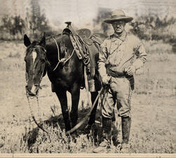 Young Theodore Roosevelt standing next to a horse.