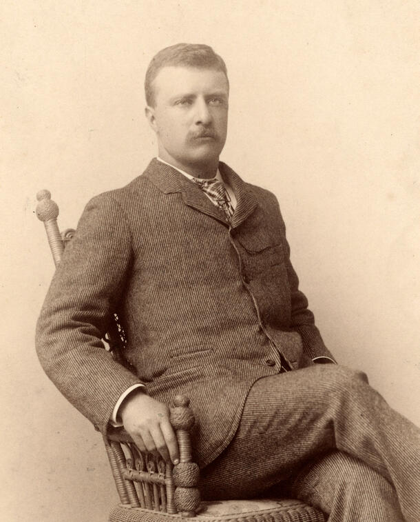 Young Theodore Roosevelt seated in a chair.