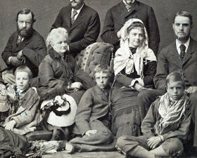 Theodore Roosevelt as a child, seated on the floor in the middle, surrounded by eight people.