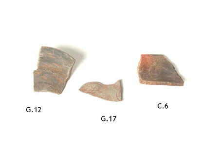 Three potsherds with a gray-colored finish with some orange-colored swirls.