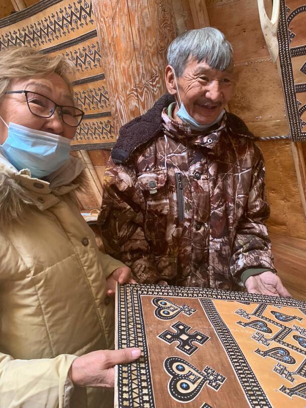 Two people hold a piece of painted wood.