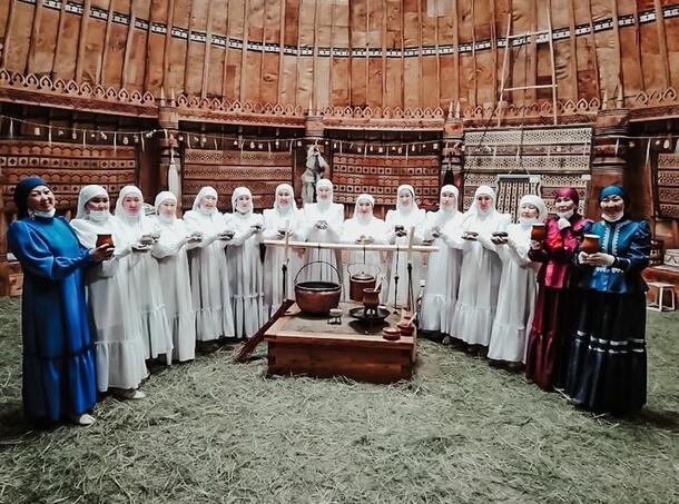 A large group of people in ceremonial dress gather inside the domed structure of the Yakut (Mo5ol-Uraha).